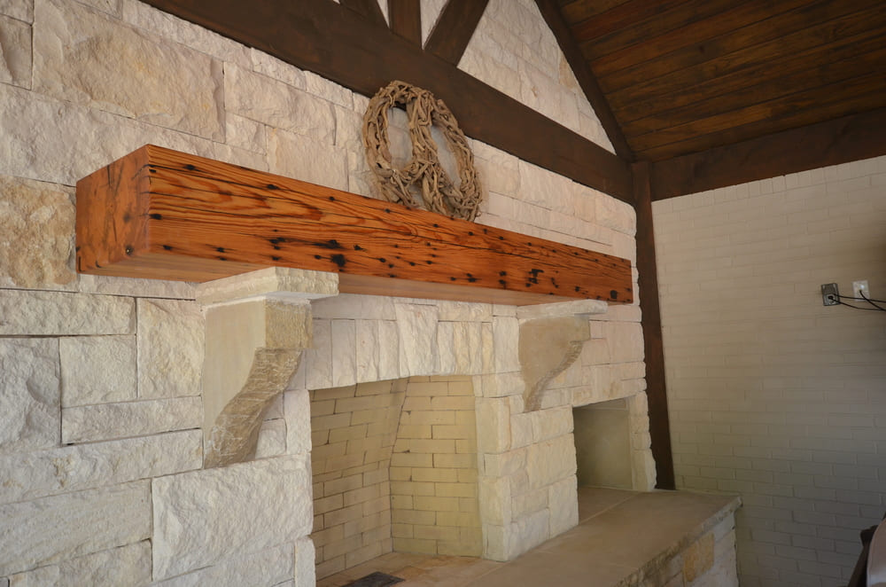 Outdoor Fireplace Featuring Wooden Shelf with Wreath on Top