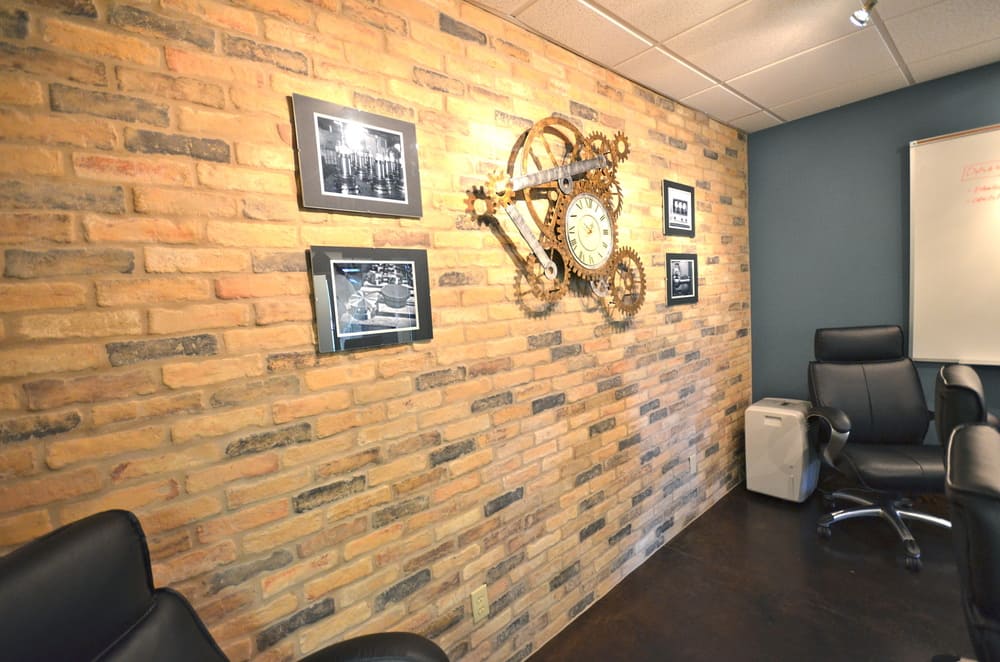 Brick Wall in Office with Ornate Clock on Wall with Four Pictures
