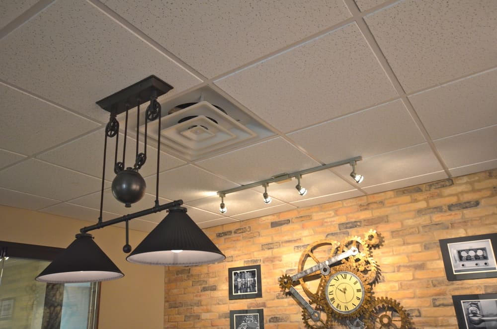 Ceiling of Office Building with Black Hanging Lights and Ornate Clock and Brick Wall